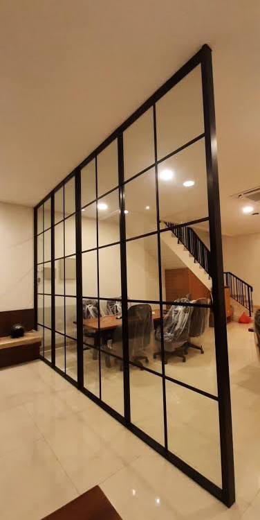 Partisi kaca berangka aluminium hitam yang membatasi ruang keluarga
